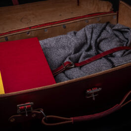 A Handmade Leather Suitcase with a red book and a yellow book in it.