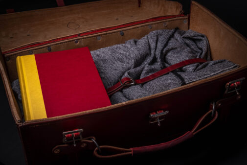 A Handmade Leather Suitcase with a red book and a yellow book in it.