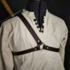 A white shirt with a brown Monster Hunter Sword Carrier strap.