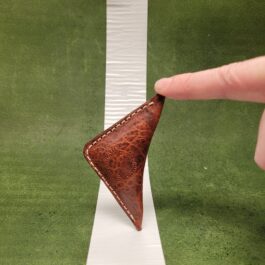 A hand holding a NFL Leather Finger Football on top of a white line.