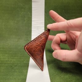 A hand holding an NFL Leather Finger Football next to a white line.