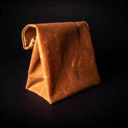 A Waxed Canvas Lunch Bag is sitting on a black surface.