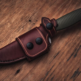 A Handmade Leather Sheath for the Benchmade Anonymous knife on a wooden table.