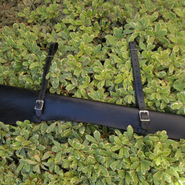 A Handmade Leather Rifle Scabbard laying on top of a lush green field.