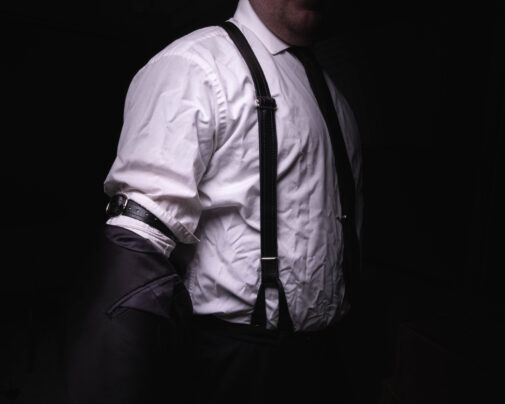 A man wearing leather dress suspenders.