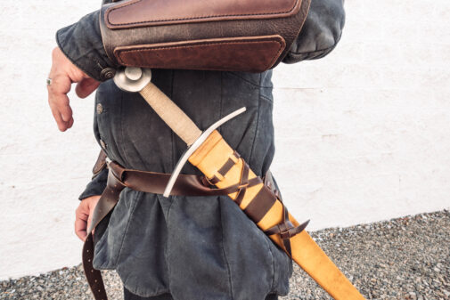 A man holding a Wood Core Scabbard for the Albion I:33 in his back pocket.
