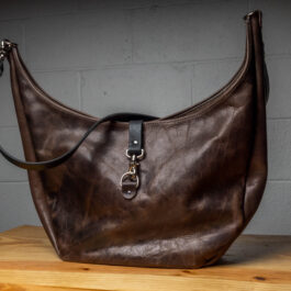 A gray leather bag on a wooden table