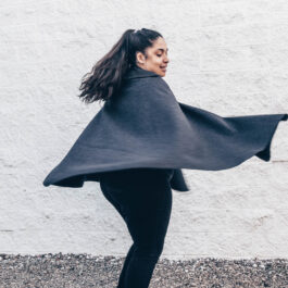 a woman twirling while wearing a wool cape
