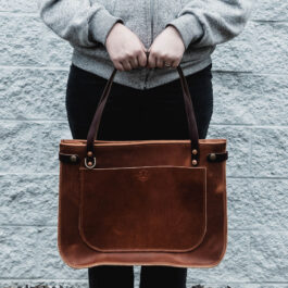 a woman holding the solvang tote in horween dublin english tan