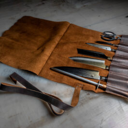A Handmade Leather Knife/Tool Roll with a knife and a pair of scissors.