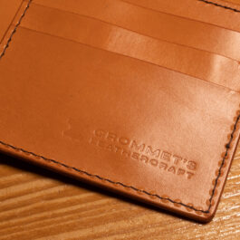 A close up of the Hermann Oak Bifold Leather Wallet With Hemmed Edge on a wooden table.