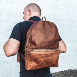 A man wearing a light brown leather backpack